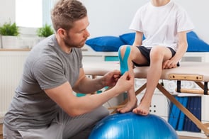 Physical therapist applying young patient medical tape